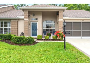 Charming home featuring a blue front door, lovely front yard, and a screened 2 car garage at 7367 Willow Brook Dr, Spring Hill, FL 34606