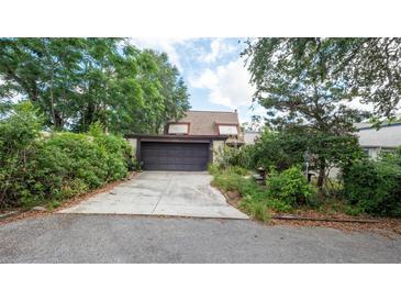 Charming home featuring a garage, driveway, and mature landscaping for added privacy and curb appeal at 7501 Woodbox Row, Hudson, FL 34667