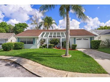 Charming single-story home featuring a well-maintained lawn, blue trim, and a pergola-covered entrance at 8021 Wildflower Row, Hudson, FL 34667