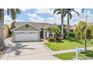 Charming single-story home with a well-manicured lawn and mature palm trees enhancing its curb appeal at 1222 Starboard Ky, Tarpon Springs, FL 34689