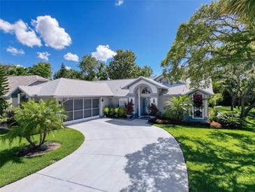 Charming single-Gathering home features a welcoming front yard, a screened garage, and a curved driveway at 13627 Glaze Brook Dr, Hudson, FL 34667