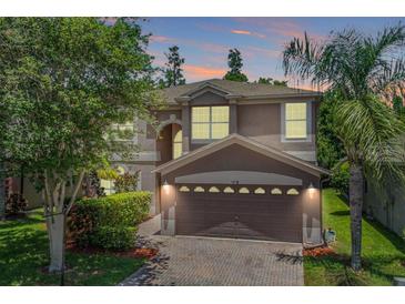 Charming two-story home featuring a brick driveway, two-car garage, and landscaped yard at 1418 Halapa Way, Trinity, FL 34655