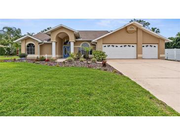 Charming single-story home with a two-car garage, blue door, and lush landscaping at 18244 Autumn Lake Boulevard, Hudson, FL 34667