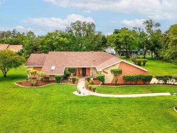 Beautiful single-story home featuring a manicured lawn, mature trees, and a welcoming walkway to the front door at 8393 Delaware Dr, Weeki Wachee, FL 34607