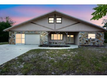 Charming single-story home featuring stone accents, a two-car garage, and a well-maintained front yard at 8568 Heather Blvd, Weeki Wachee, FL 34613