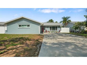Charming single-story home with a well-maintained lawn, long driveway and decorative landscaping at 1004 Peninsula Ave, Tarpon Springs, FL 34689