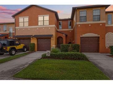 Inviting townhome featuring an attached garage, landscaped yard, and a warm, colorful exterior at 1108 Blackwater Dr, Wesley Chapel, FL 33543