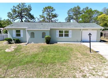 Charming single-story home featuring a well-manicured lawn, windows with white shutters and one-car garage at 13180 Lawrence St, Spring Hill, FL 34609