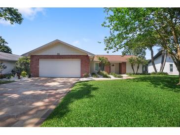 Charming single-story home featuring a brick facade, manicured lawn, and spacious two-car garage at 2866 Thistle N Ct, Palm Harbor, FL 34684