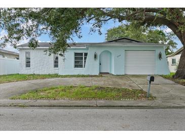 Charming light blue home featuring a garage and a quaint arched doorway at 9744 Rainelle Ln, Port Richey, FL 34668