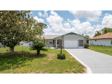 Charming single-story home featuring a well-maintained lawn, mature tree, and a spacious driveway leading to an attached garage at 10386 Myra St, Spring Hill, FL 34608