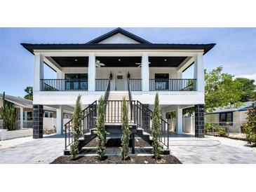 Stunning two-story home featuring a charming front porch, black railings, and well-maintained landscaping at 111 E Cedar St, Tarpon Springs, FL 34689