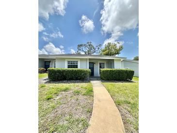 Charming home with well-maintained lawn, trimmed hedges, and a concrete walkway leading to the front door at 12511 Dearborn Dr, Hudson, FL 34667