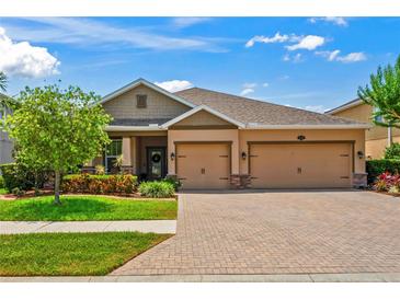 Charming home featuring a well-manicured lawn, brick driveway, and a two-car garage, perfect for suburban living at 1760 Fox Grape Loop, Lutz, FL 33558