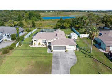 Spacious home with a large yard, pool, and scenic views of the surrounding lake and greenery at 2585 Waterfall Dr, Spring Hill, FL 34608
