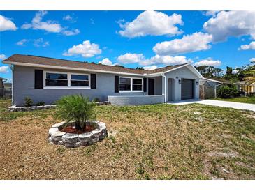 Charming single-story home features a gray painted exterior, dark shutters, and a well-manicured front yard at 6306 Aberdeen Ave, New Port Richey, FL 34653