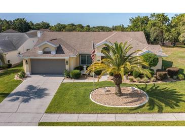 Charming one-story home featuring a well-manicured lawn with a palm tree and a classic two-car garage at 1049 Larkin Rd, Spring Hill, FL 34608