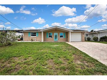 Charming single-story home featuring a brick facade, turquoise shutters, and a well-maintained front yard at 12637 2Nd Isle, Hudson, FL 34667