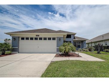 Inviting single-Gathering home featuring a spacious two-car garage, blue-grey facade and lush green lawn at 14011 Shoal Dr, Hudson, FL 34667