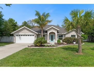 Charming single-story home featuring a two-car garage, beautifully landscaped yard, and a quaint, welcoming entrance with a teal door at 4009 Clear Spring Rd, Brooksville, FL 34604