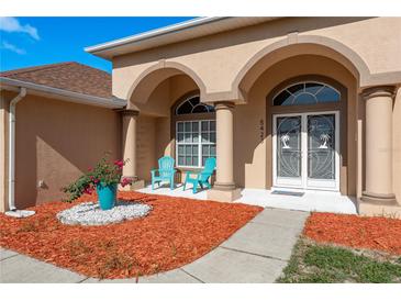 Inviting front porch with stylish columns, tiled floor, seating, and beautiful landscaping at 5423 Abagail Dr, Spring Hill, FL 34608