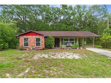 Charming single-story home with brick accents, a cozy carport, and lush greenery in a serene setting at 8102 Fort Dade Ave, Brooksville, FL 34601