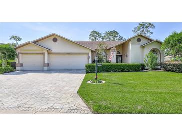Charming single-story home with a well-manicured lawn, beautiful pavers, and a two-car garage at 8132 Summersong Ct, Spring Hill, FL 34606