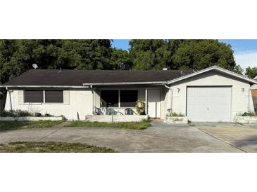 Cozy one story home featuring a front yard, an attached garage, and a front porch with lawn chairs at 11726 Oceanside Dr, Port Richey, FL 34668