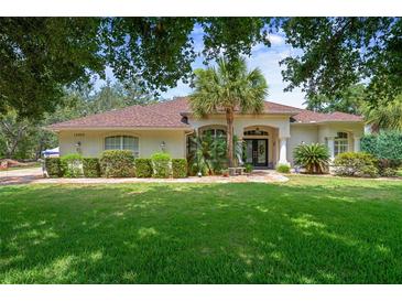 Charming home featuring lush landscaping, a well-maintained lawn, and a welcoming entrance at 12403 Moneta Rd, Weeki Wachee, FL 34614