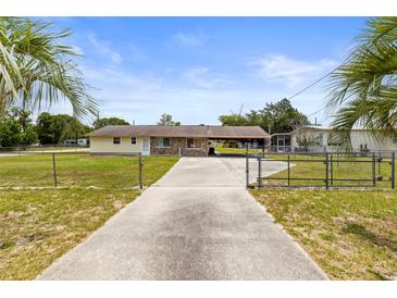 Charming single story home with a long driveway and front yard behind a chainlink fence at 12936 Parkwood St, Hudson, FL 34669