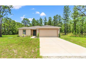 Charming single-Gathering home with a well-manicured lawn, two-car garage, and mature trees in the background at 15414 Green Jay Rd, Weeki Wachee, FL 34614