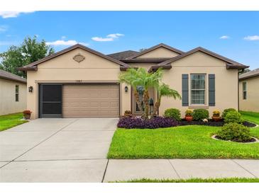 Charming single-story home featuring a well-manicured lawn, neutral paint, and an attached two-car garage at 1987 Trillium Blvd, Brooksville, FL 34604