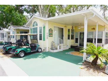 Charming home exterior featuring a covered porch, well-manicured landscaping, and a convenient golf cart parking area at 21040 Lazy Days Cir, Lutz, FL 33558