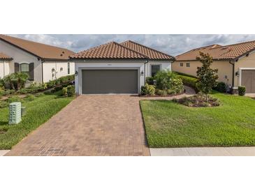 Charming single-story home with a brick driveway and well-manicured landscaping and gray garage door at 3051 Francoa Dr, Odessa, FL 33556