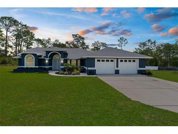 Beautiful single-story home with a well-manicured lawn, arched entryway, and attached three-car garage at 8084 Nightingale Rd, Weeki Wachee, FL 34613