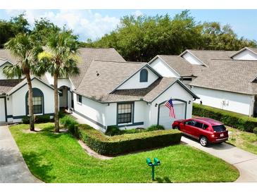 Charming single-story home with manicured lawn, trimmed hedges, and a red car parked in the driveway at 9200 Turnberry Ct, New Port Richey, FL 34655
