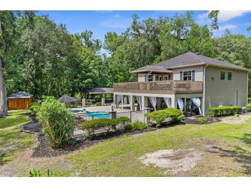 A beautiful home featuring an outdoor pool with a deck, luscious landscaping, and plenty of shade trees at 12085 Stringer Rd, Brooksville, FL 34601