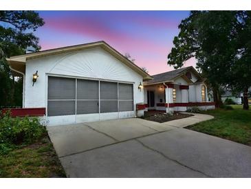 Charming single-story home with white exterior and a two-car garage and driveway at 11364 Orangewood Ct, Spring Hill, FL 34609