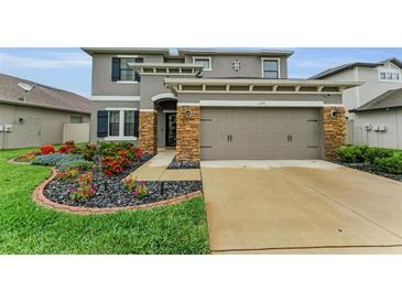 Charming two-story home featuring a two-car garage, stone accents, beautiful flower beds, and a well-manicured lawn at 1236 Ketzal Dr, Trinity, FL 34655