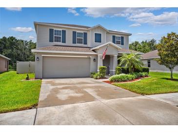 Charming two-story home features a manicured lawn, gray siding, blue shutters and an attached two car garage at 18566 Hunters Meadow Walk, Land O Lakes, FL 34638
