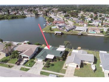 Waterfront home featuring lush landscaping, private boat dock, and serene lake views from an elevated perspective at 3140 Jackson Dr, Holiday, FL 34691