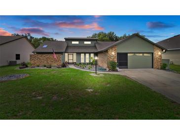 Charming single-story home featuring a landscaped front yard, brick accents, and a two-car garage at 35046 Smoketree Ln, Dade City, FL 33523