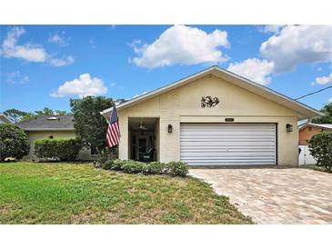 Charming single-story home with a brick driveway, American flag, and well-maintained landscaping at 4072 Everett Ave, Spring Hill, FL 34609