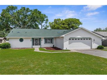 Charming single-story home with a green roof, well-maintained lawn, and attached two-car garage at 5035 Harbinger Rd, Spring Hill, FL 34608
