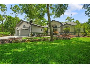 Charming home featuring lush green lawn, rock garden, mature trees and welcoming curb appeal at 8518 Quail Hollow Blvd, Wesley Chapel, FL 33544
