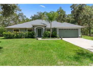 Charming single-story home with lush green lawn and meticulously maintained landscaping and a side entry garage at 10149 Rockbay Rd, Brooksville, FL 34601