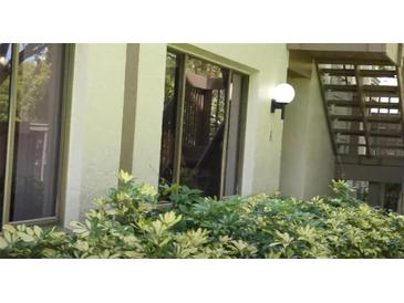 Exterior angle of condo showing windows, lighting fixture, greenery, and stairs at 13010 Wedgewood Way # A, Hudson, FL 34667