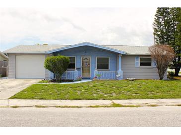 Charming single-story home featuring a blue front facade, well-maintained lawn, and attached garage at 3151 Wellington Dr, Holiday, FL 34691