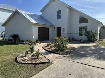 Stunning two-story home featuring a well-manicured yard, lush garden beds, and a charming brick walkway at 4104 Pine Dale Ct, Hernando Beach, FL 34607