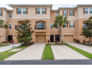 Townhouse exterior with two-car driveways, garages, balcony, neutral paint, dark accents, and manicured landscaping at 5520 White Marlin Ct, New Port Richey, FL 34652
